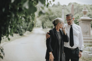 Husband trying to comfort his wife at a graveyard